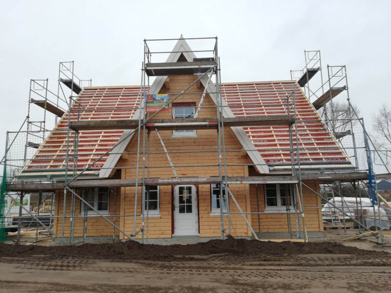 Haus, noch nicht gestrichen, im Bau mit Grüst. Vor dem Haus ist noch alles voller Sand.